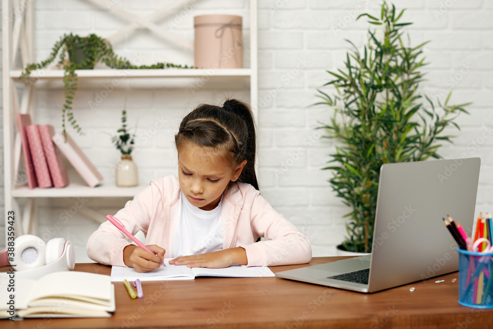 adorable little child girl using laptop for studying online . online lesson at home. social distance during quarantine
