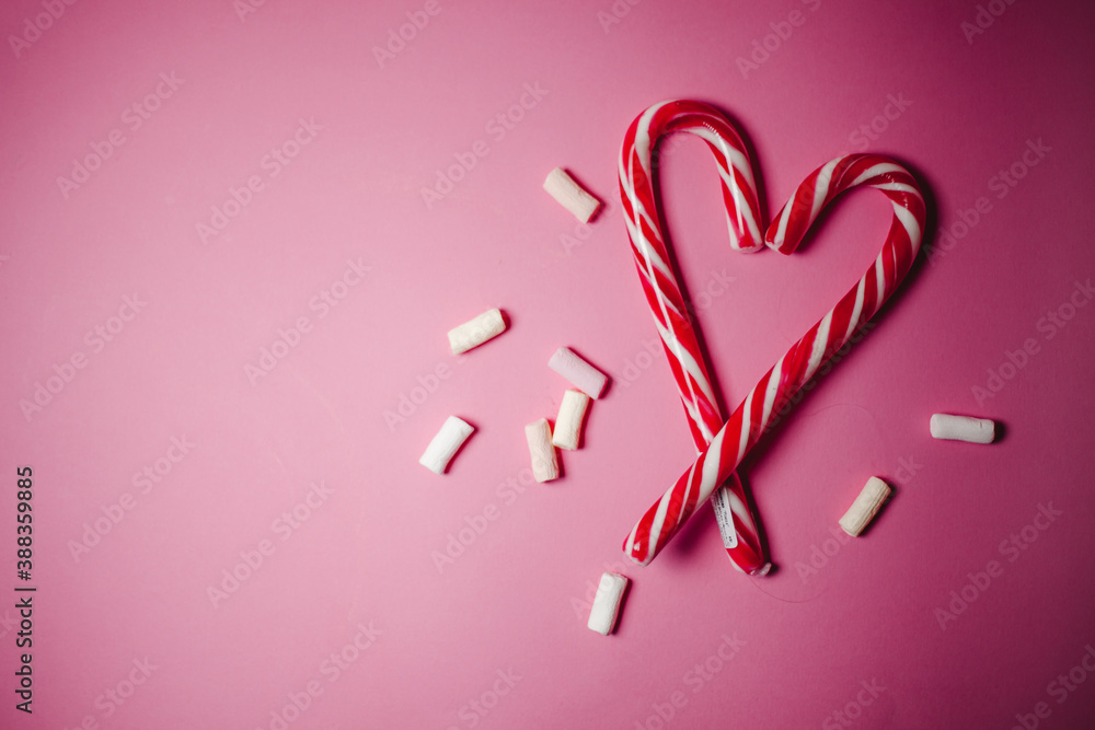 two lollipops in heart shape on pink background. Gifts for the New year and Christmas. top view