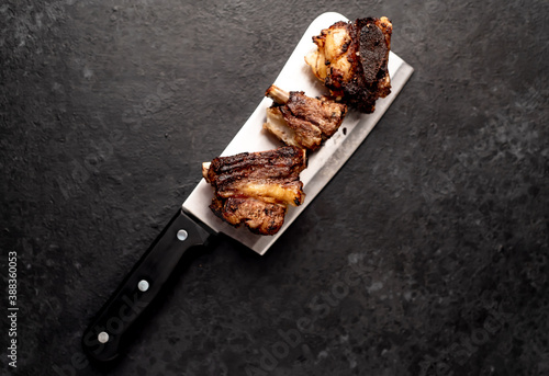 grilled beef ribs on a meat knife on a stone background