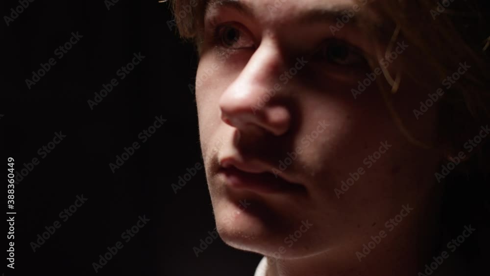 White teen boy student looks up in the dark with a sad, lonely expression White teen boy student looks up in the dark with a sad, lonely expression