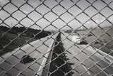 Close up pattern of wire mesh fence. Highway view at background. Transportation concept. Black and white.