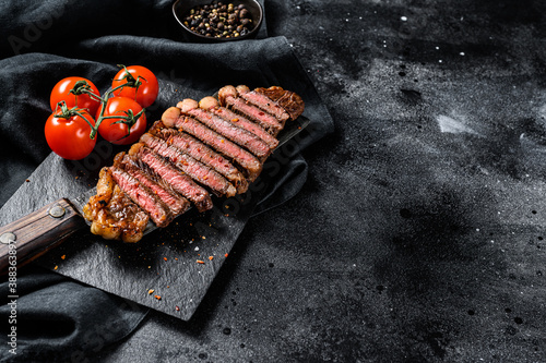Grilled sliced sirloin steak on a meat cleaver. Black background. Top view. Copy space