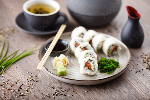 Sushi maki rolls Philadelphia with salmon  creamy cheese and avocado on a plate with chopsticks  soy sauce  wasabi and ginger. Japanese traditional seafood served for lunch in modern restaurant