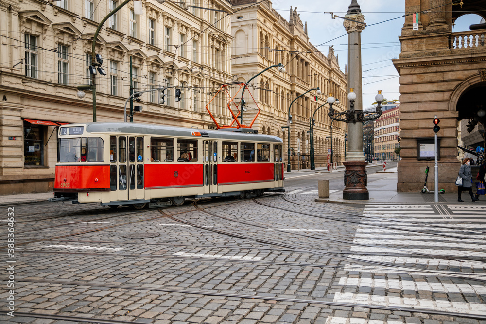 Red retro tram at National avenue during the autumn day, Cafe Slavia at Narodni trida street, traditional coffee shop in Prague opposite to National Theatre. Czech Republic