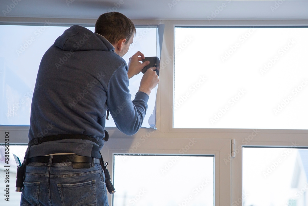 Fototapeta premium Installing window film in the office. Protection from ultraviolet radiation. Protective film.