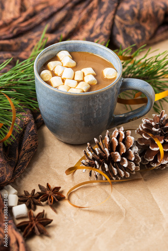 A Cup of coffee or cocoa with marshmallows with Christmas tree or New year decor. Winter still life with a warm drink, scarf, anise stars and cones