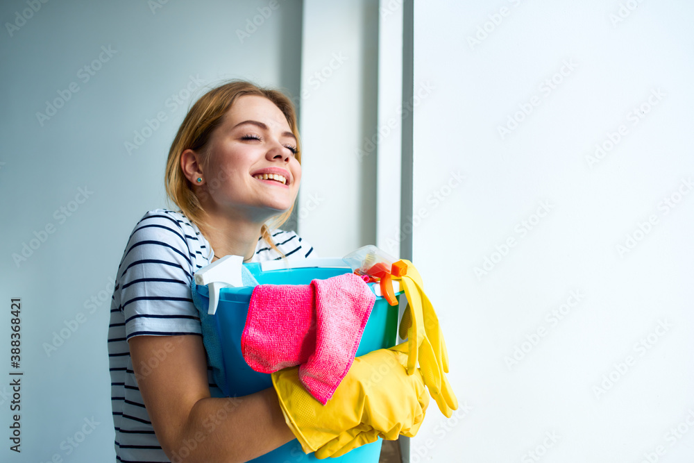 Woman with a bucket of cleaning supplies near the window taking care of the house Woman with a bucket of cleaning supplies near the window taking care of the house