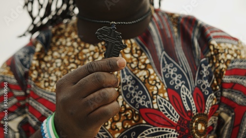 African man with traditional clothes showing neckchain pendant in the shape of africa. High quality photo