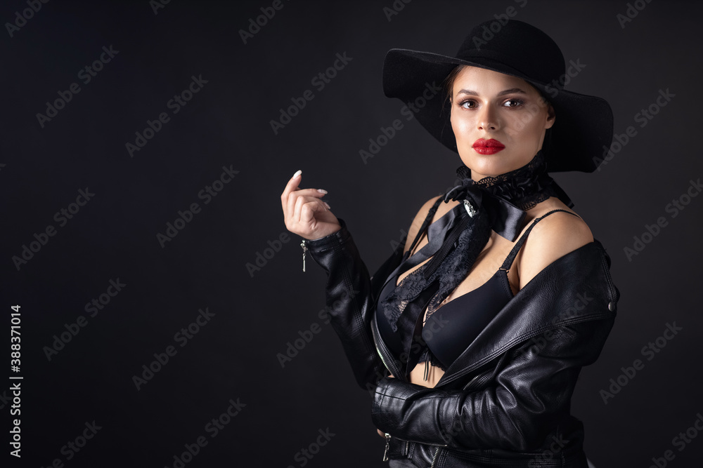 Woman in big black hat and jacket, studio portrait, dark background Woman in big black hat and jacket, studio portrait, dark background