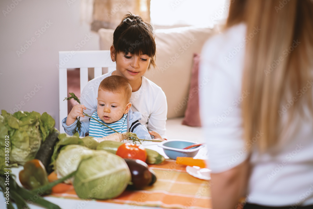 Fototapeta premium Young mother and children preparing meal with healthy food