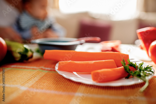 Close-up of kid eating carrot during breakfast. Healthy diet for child concept 