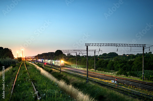 Freight train with lights on while moving in the evening