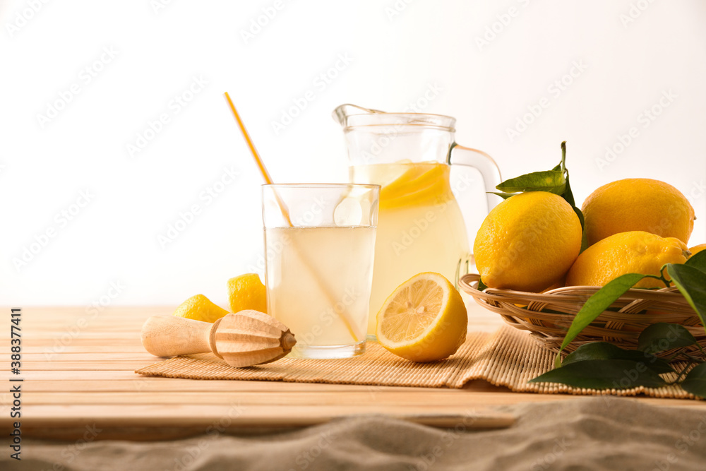 Jug and glass with lemonade on table and sand Jug and glass with lemonade on table and sand