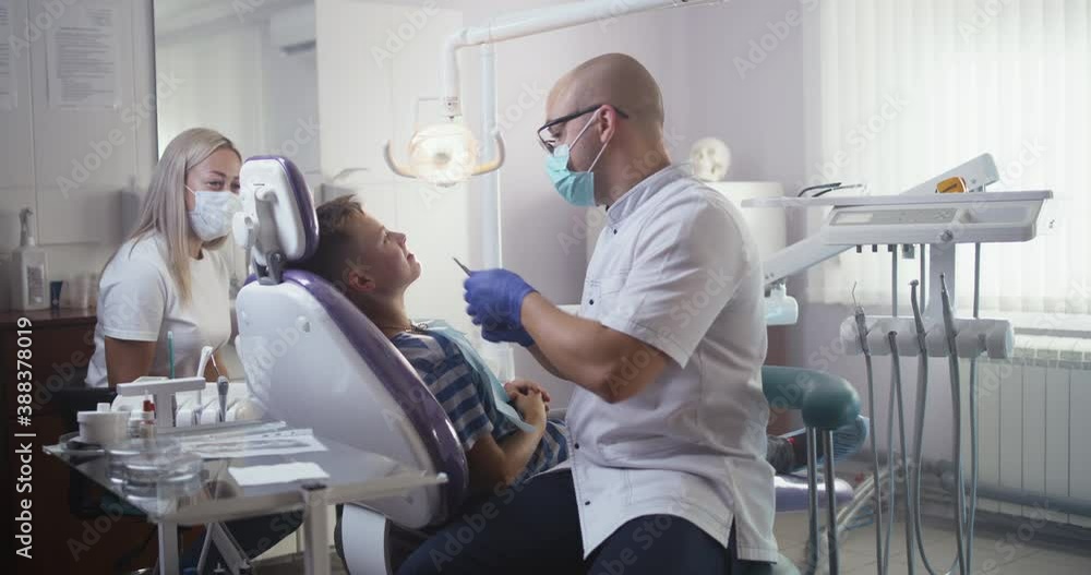 Dentist checking healthy teeth of teen boy Dentist checking healthy teeth of teen boy