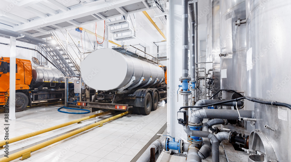 Milk tanker truck pumps products into steel storage tanks, dairy