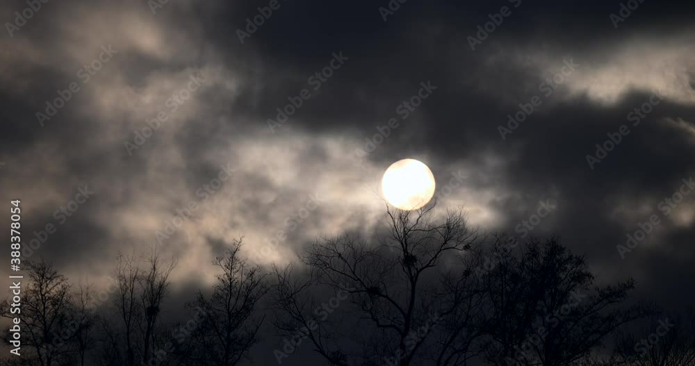 Sun Behind Dark Gray Clouds Moving Fast. Round Solar Disk. Strong Wind Weather Climate Evening Dusk Grey Sky Sun Behind Dark Gray Clouds Moving Fast. Round Solar Disk. Strong Wind Weather Climate Evening Dusk Grey Sky