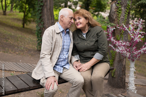 Senior couple together in park in spring or autumn. Beautiful love relation and care of retirement old people.