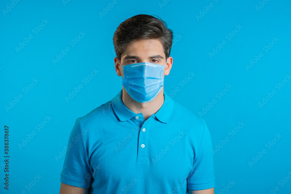 Portrait of handsome man in medical mask looking to camera. Guy in studio on bright background. Coronavirus, covid-19, epidemic reality concept. Portrait of handsome man in medical mask looking to camera. Guy in studio on bright background. Coronavirus, covid-19, epidemic reality concept.