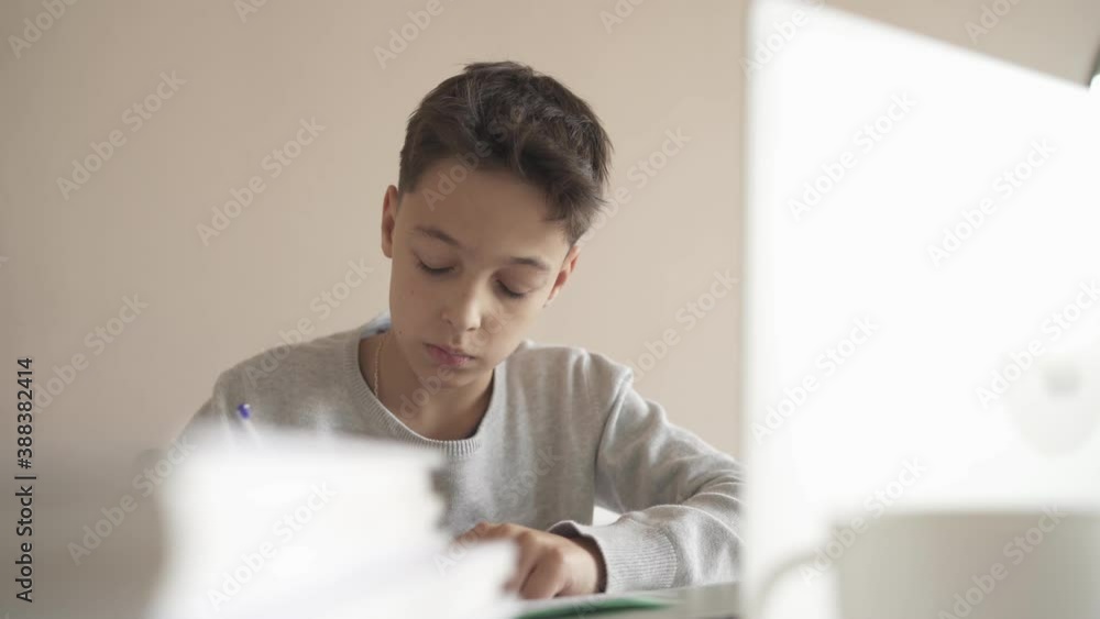A child does homework using a laptop while sitting at home in the kitchen at the table. Online Technology A child does homework using a laptop while sitting at home in the kitchen at the table. Online Technology