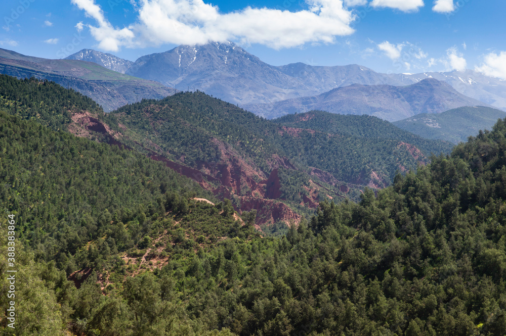 Landscape with slightly snowy mountains and blue cloudy sky in the Morocco Atlas Mountains in summer in the fertile Ourika Valley near Marrakech, Morocco