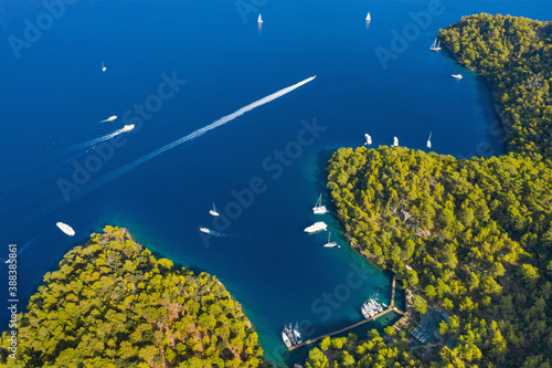 Fototapeta Naklejka Na Ścianę i Meble -  aerial view to curved coastline with yachts at sea and running speed boat