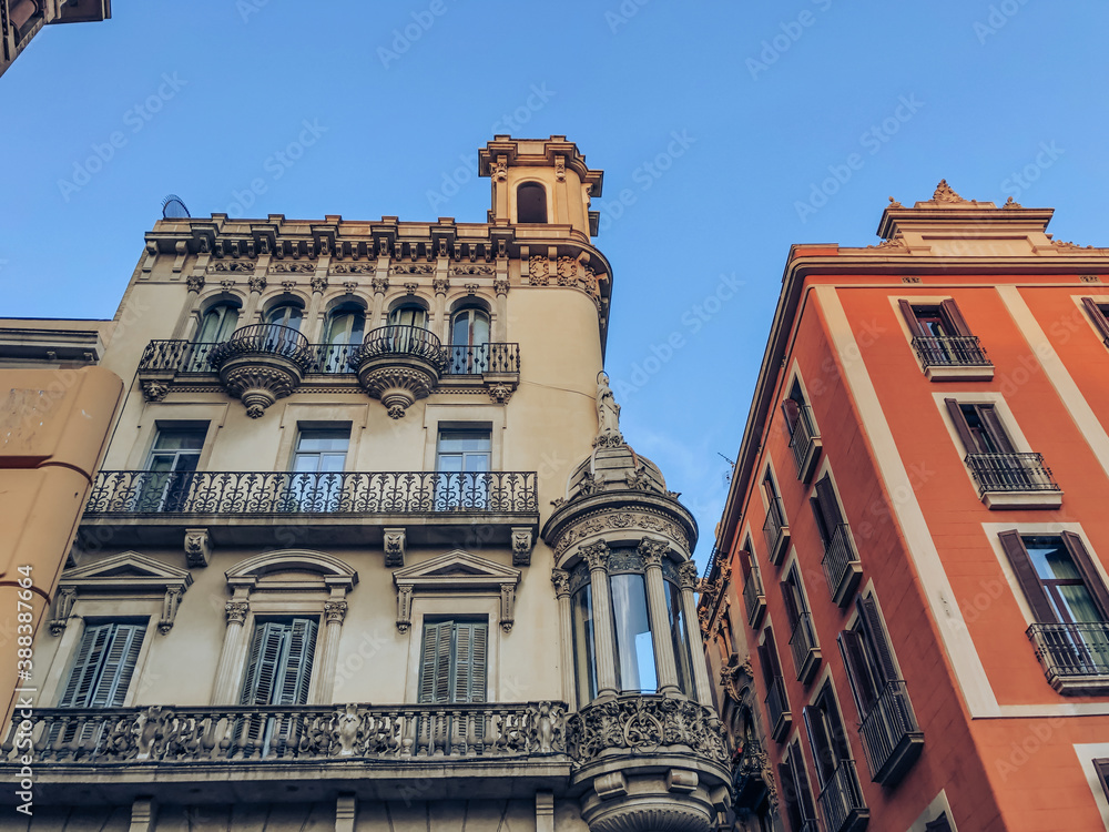 Fototapeta premium Facade of buildings in the center of the Spanish city of Barcelona. The building is gray and orange against the blue sky.