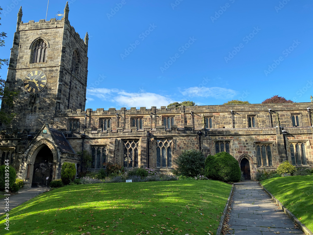 Very old church, with grass lawns, set against a vivid blue sky in, Skipton, Yorkshire, UK