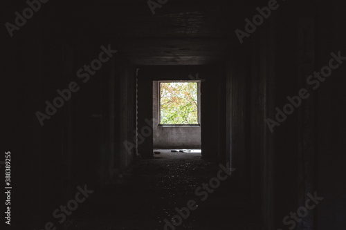 Dark cold weathered abandoned floor way with lighted window in the end. From darkness to new beginning