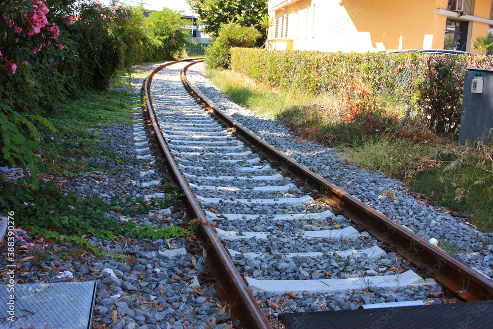 Fototapeta premium gravel and stones along the train tracks next to a house in the green bushes