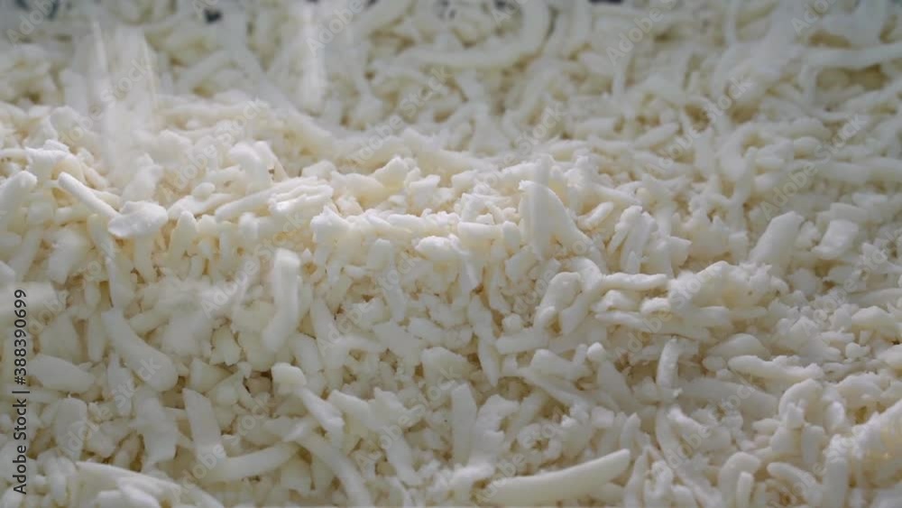 grated pizza mozzarella cheese falls in a plate from top. grated pizza mozzarella cheese falls in a plate from top.