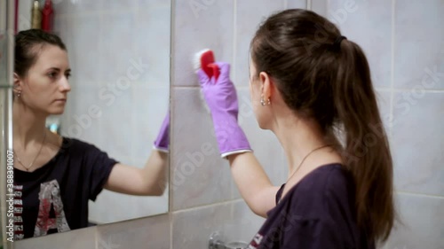 Young beautiful woman is tired of cleanig her old bathroom and dreams of moving to another house. Looking at the camera with a tired look photo