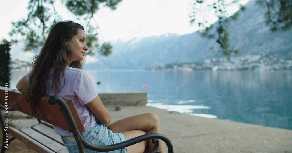 happy woman sits on a wooden bench and considers beautiful views of the lake and mountains. High quality 4k footage happy woman sits on a wooden bench and considers beautiful views of the lake and mountains. High quality 4k footage