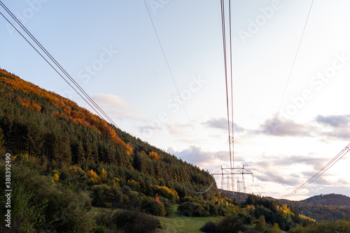 Autumn sunset orange green vibrant landscape rural power lines clouds blue sky hillside forest trees beautiful bulgaria