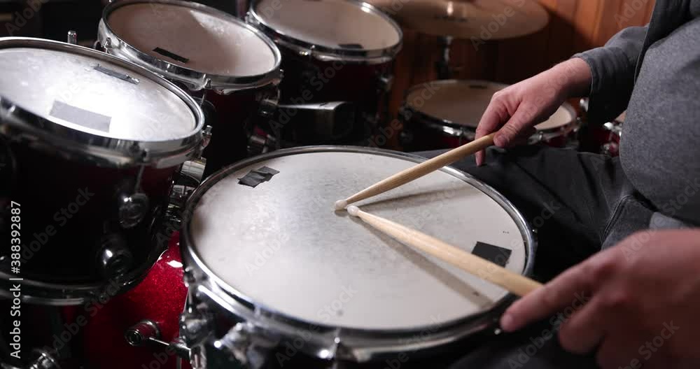 Drumsticks resting on red drums. One single beat is played in slow motion Drumsticks resting on red drums. One single beat is played in slow motion
