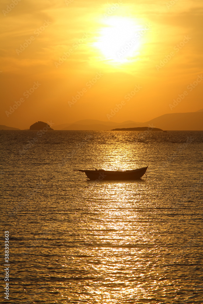 A lone sailboat at sunset. Atmospheric seascape with orange sun.