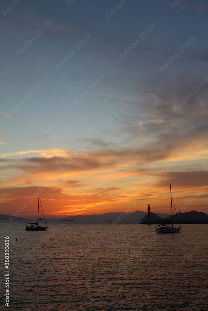 Seascape at sunset. Lighthouse on the coast. Seaside town of Turgutreis and spectacular sunsets
