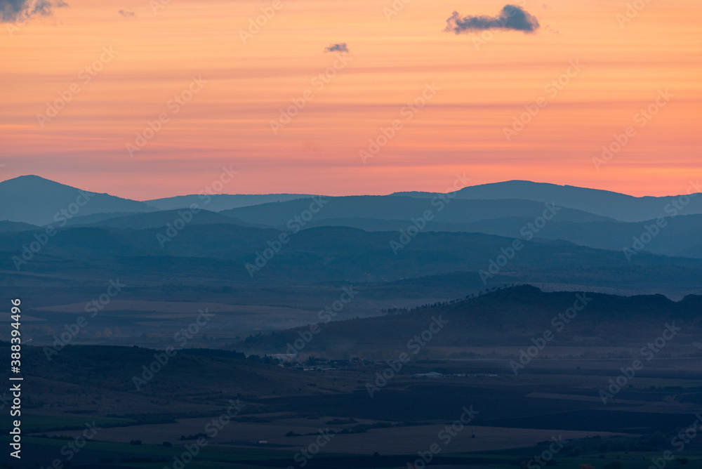 Obraz premium Landscape sunset colors over mountains and hills orange red yellow blue shades natural beauty bulgaria rural