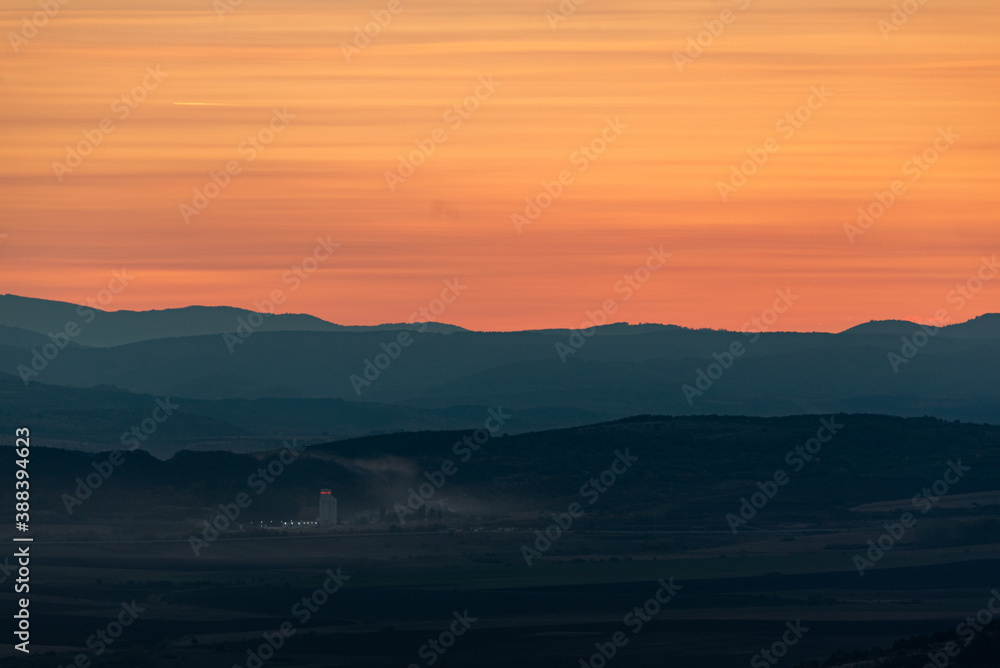 Wonderful landscape sunset clouds red orange yellow mountains fog industrial building dirty air pollution detail