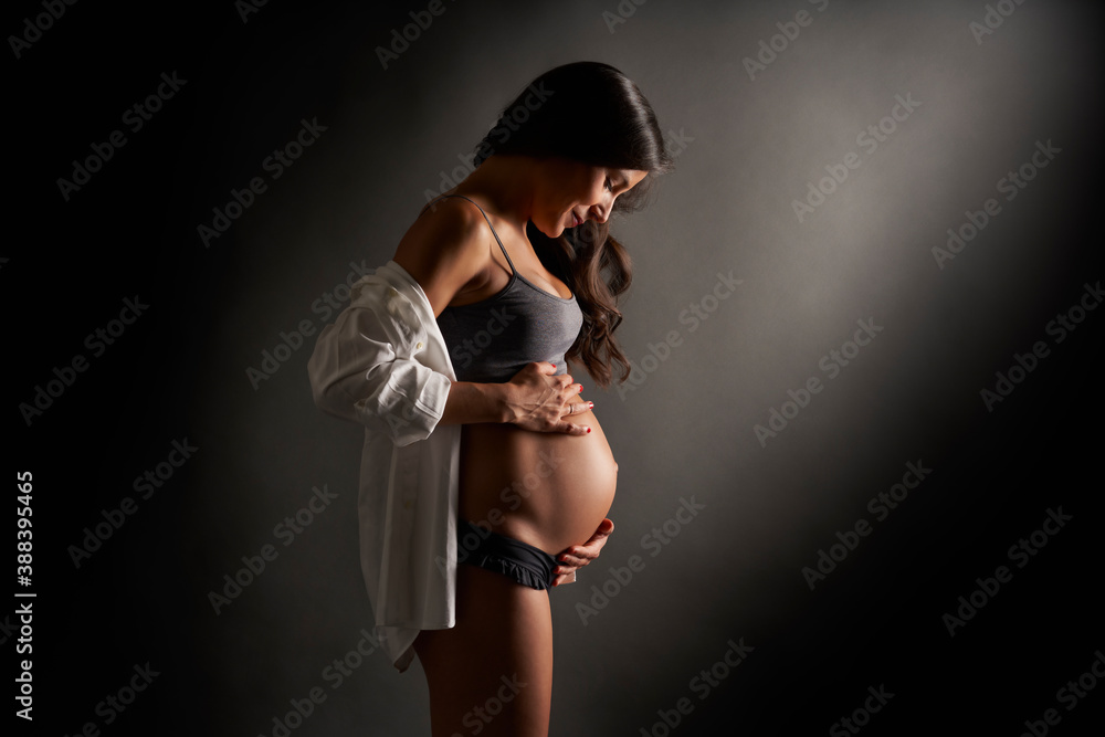 Young pregnant dancer posing holding her belly with her hands - obrazy, fototapety, plakaty 