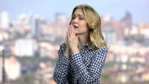 Depressed young woman holding hands on head. Anxious girl on blurred city background. photo