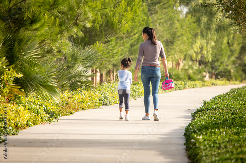 Mother and young daughter walking to school with lunch pail photo