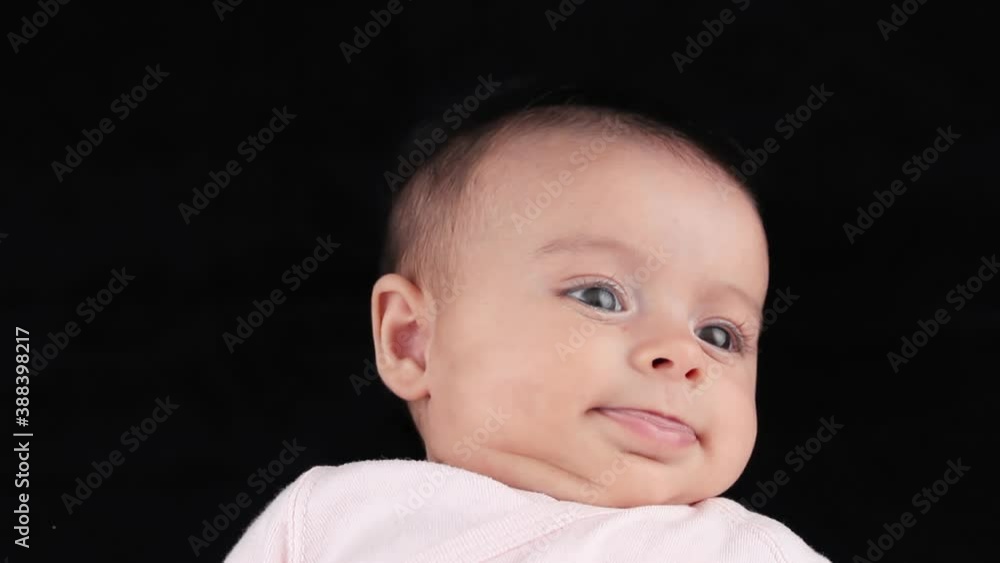 Young baby moving and making funny face expressions against a black background Young baby moving and making funny face expressions against a black background
