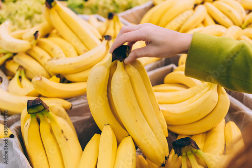 Girl holding a bunch of bananas in the supermarket.