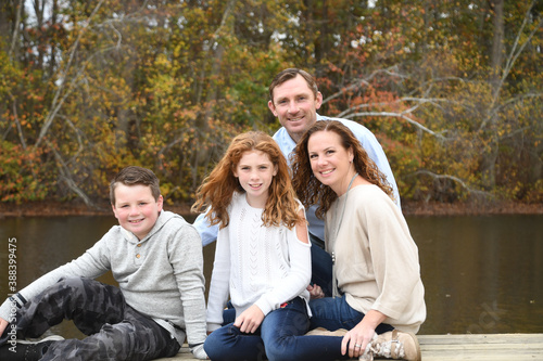 Autumn family portrait by the lake with mom, dad, son and daughter. 