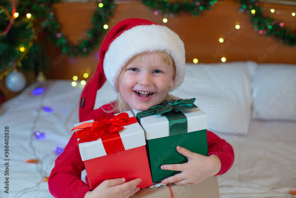 Happy little girl in Santa Claus hat received a Christmas present