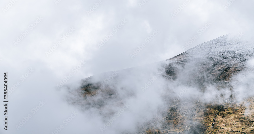 Mountain ridge with fog and clouds. Foggy landscape. Winter nature background with white space for copy space.