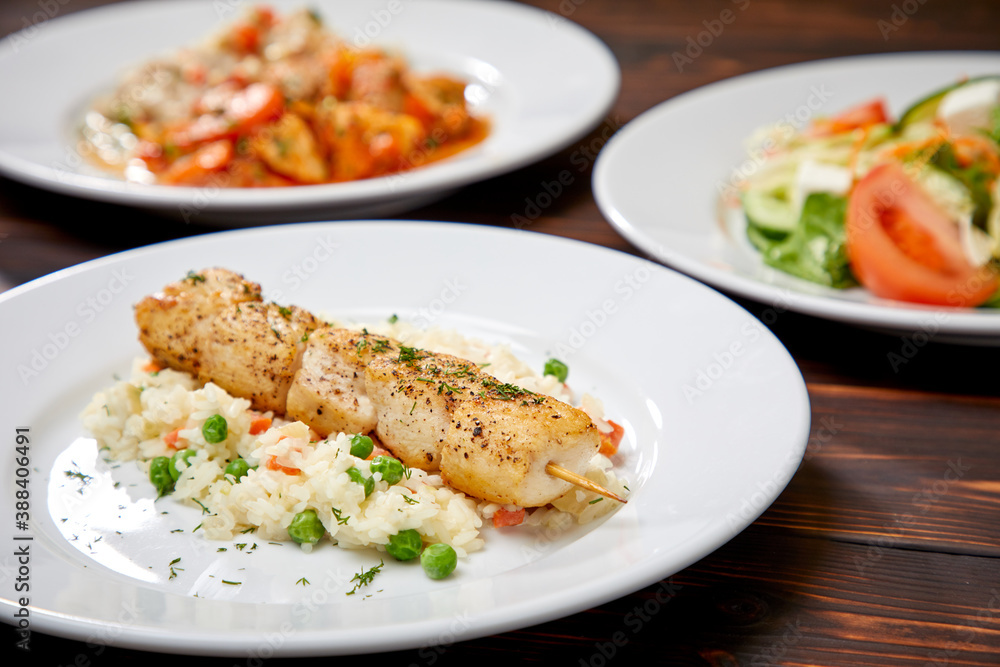 chicken kebab with rice and vegetables on the wooden background