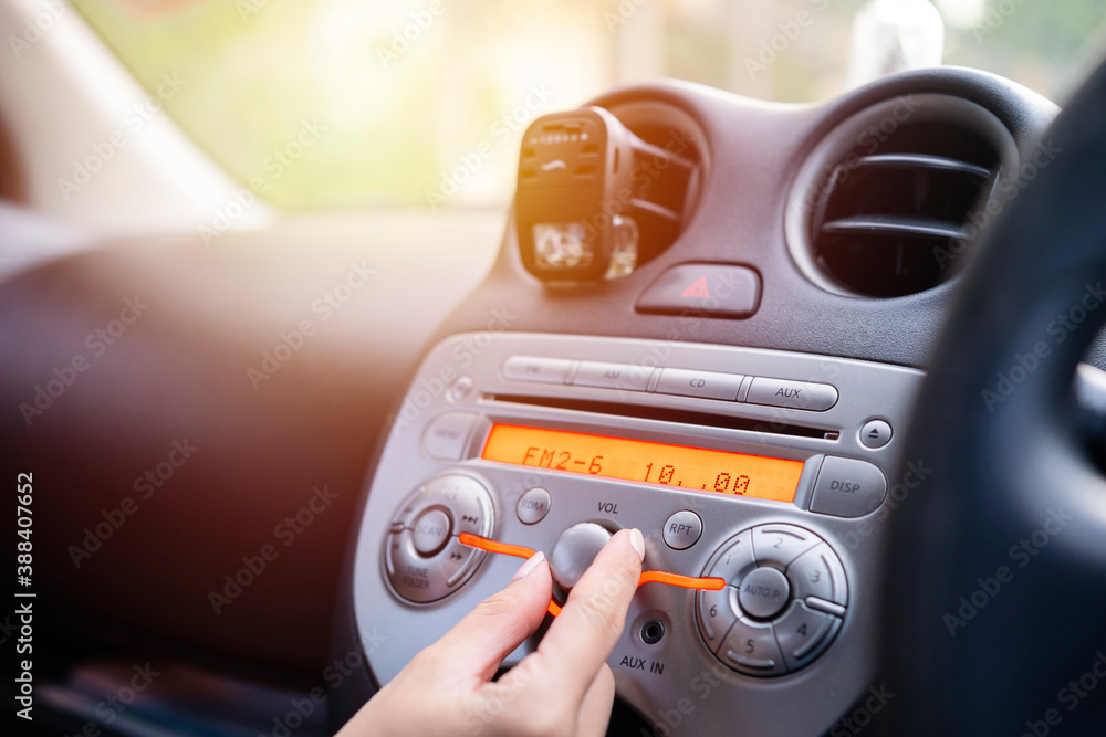 Women turning button on car radio for listening to music