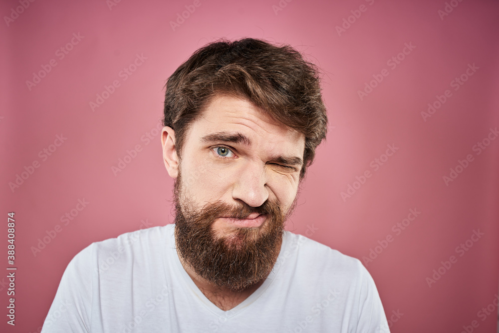 bearded man in white t-shirt emotions displeased facial expression studio pink background