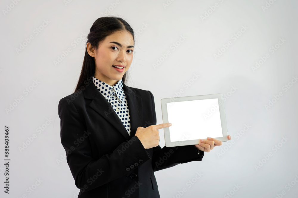 Portrait of an Asian businesswoman wearing a black suit. Hold an empty tablet to put text, images. Gray isolated background
